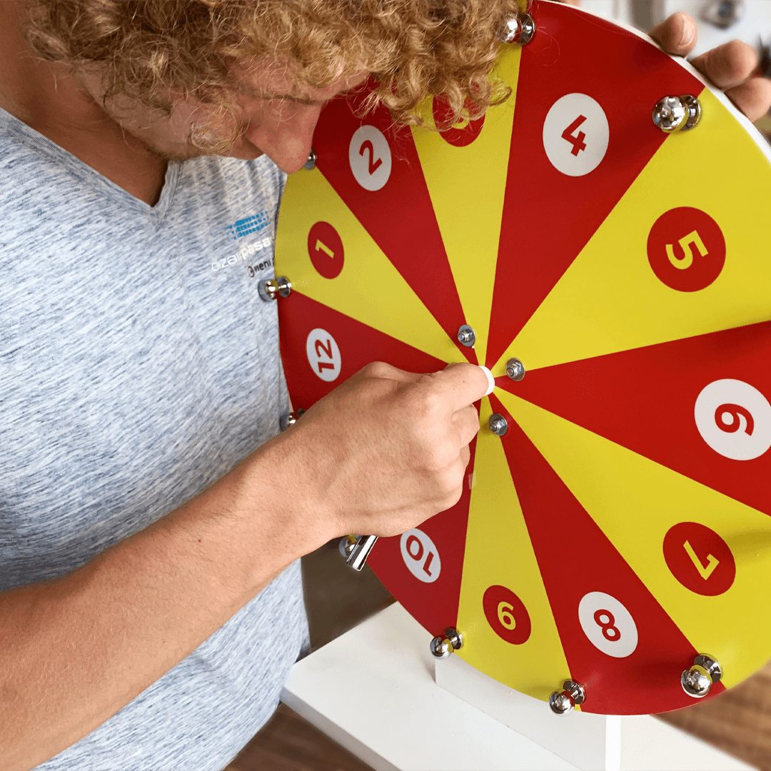 Person spinning a red and yellow numbered prize wheel of fortune