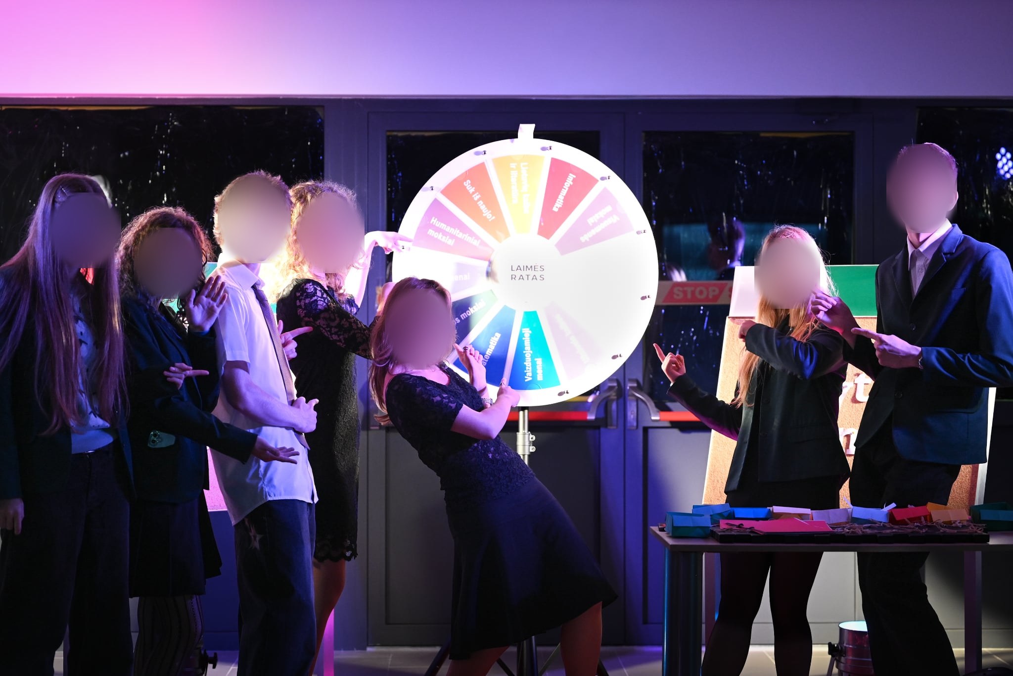 Group of people pointing at a colorful prize wheel of fortune at a school event